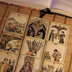 Vintage tarot cards arranged on a bamboo mat with an open book nearby.